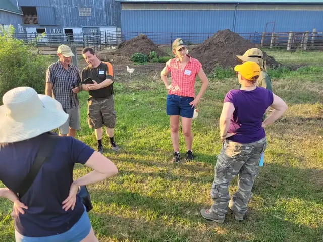 Visitors in sun hats stand on the grass at Good Trouble Grove while the farmers talk them through the farm